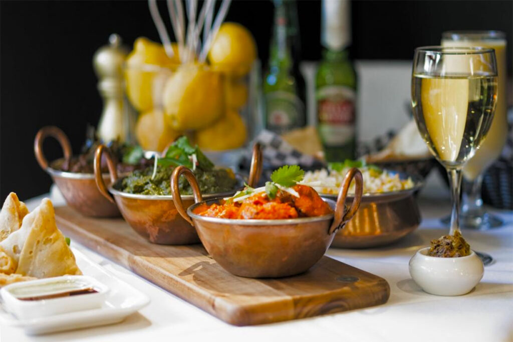 Curries in copper bowls with samosas and chutney at UTSAV, Yorkville