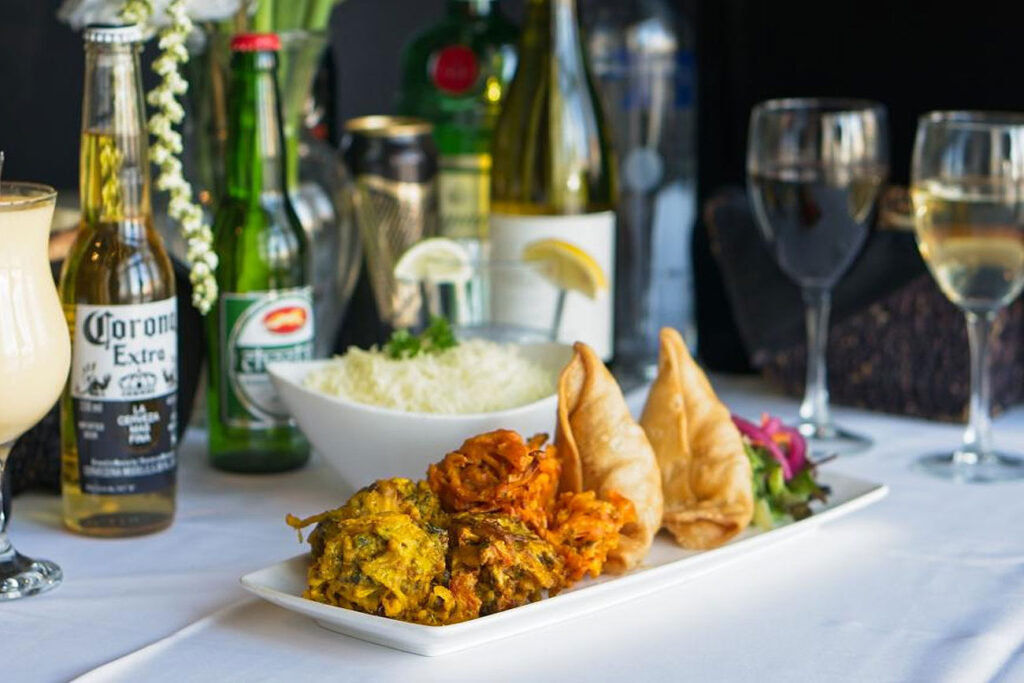 Vegetable pakoras, onion bhaji and samosas on a table set for dinner at UTSAV